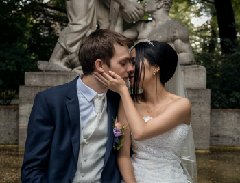 Das Brautpaar küsst sich vor einem Brunnen